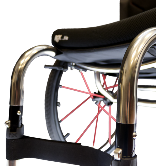 Close-up of a wheelchair with a black seat cushion, polished silver metal frame, black armrests, and red wheel spokes against a white background.