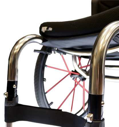 Close-up of a wheelchair with a black seat cushion, polished silver metal frame, black armrests, and red wheel spokes against a white background.